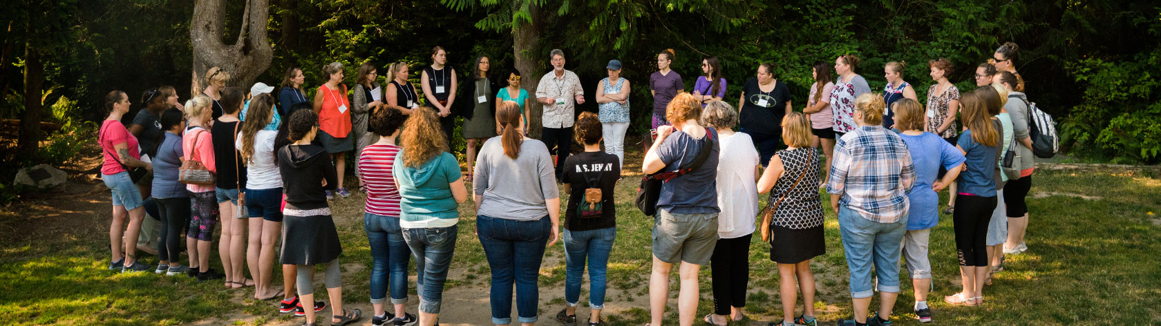 Attendees circled around a presenter in the woods