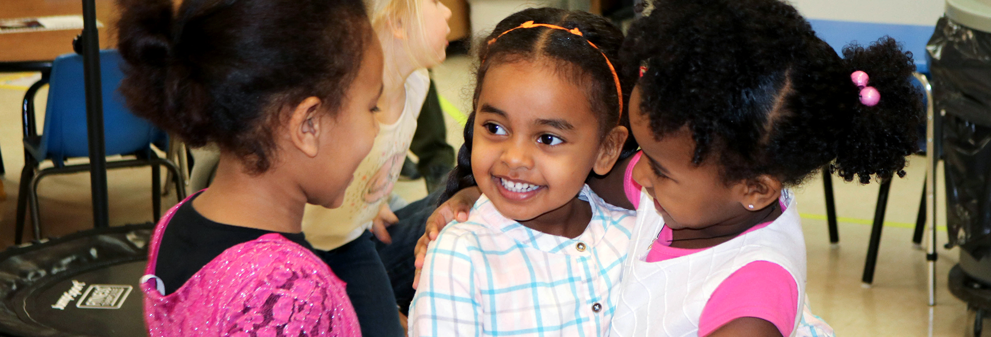 Three children who are close friends are smiling and hugging each other